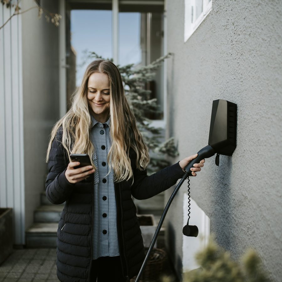 Kvinne bruker Easee hjemmelader montert til husvegg