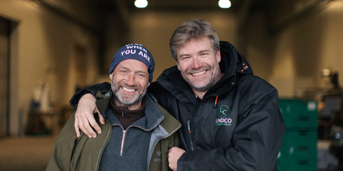 To menn som smiler i kameraet foran et grønnsakslager i Ski