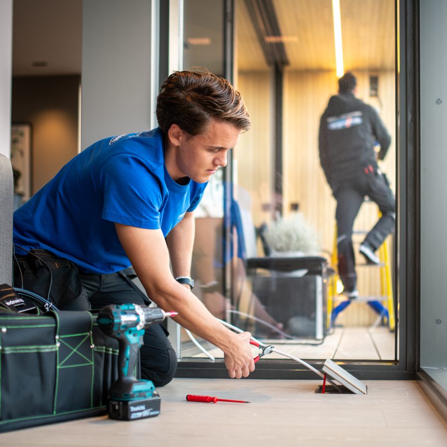 en elektriker legger skjult anlegg i stuen på et hus