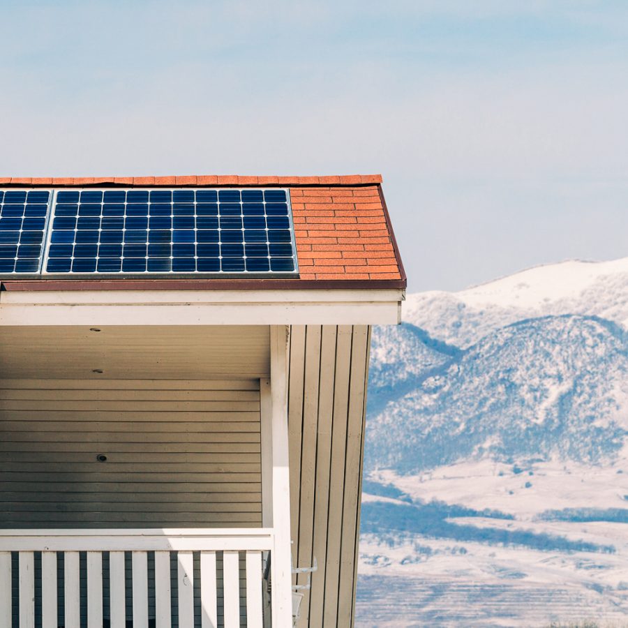 Solcellepanel på leiligheter med snødekte fjell i bakgrunn