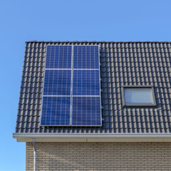 Solcellepanel på mørkt hustak over blå himmel.