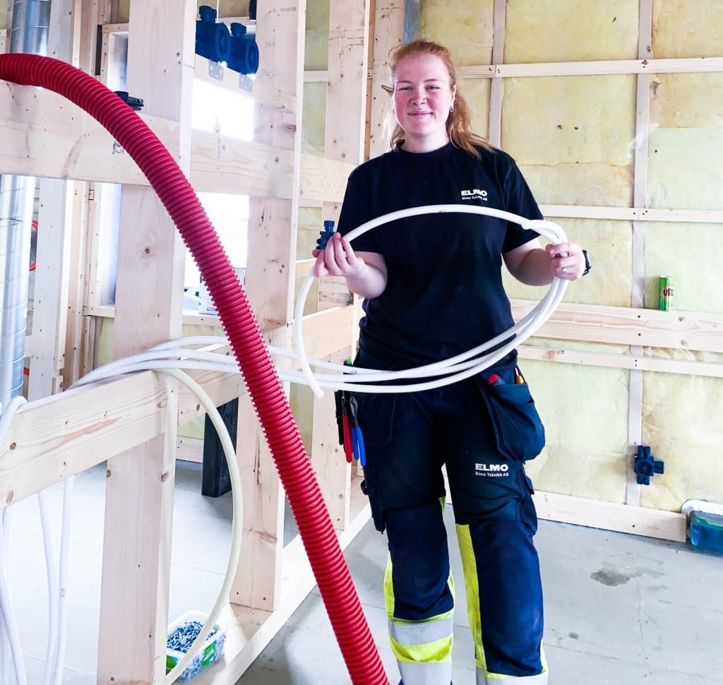 Ung kvinnelig elektriker på jobb i byggkonstruksjon. 