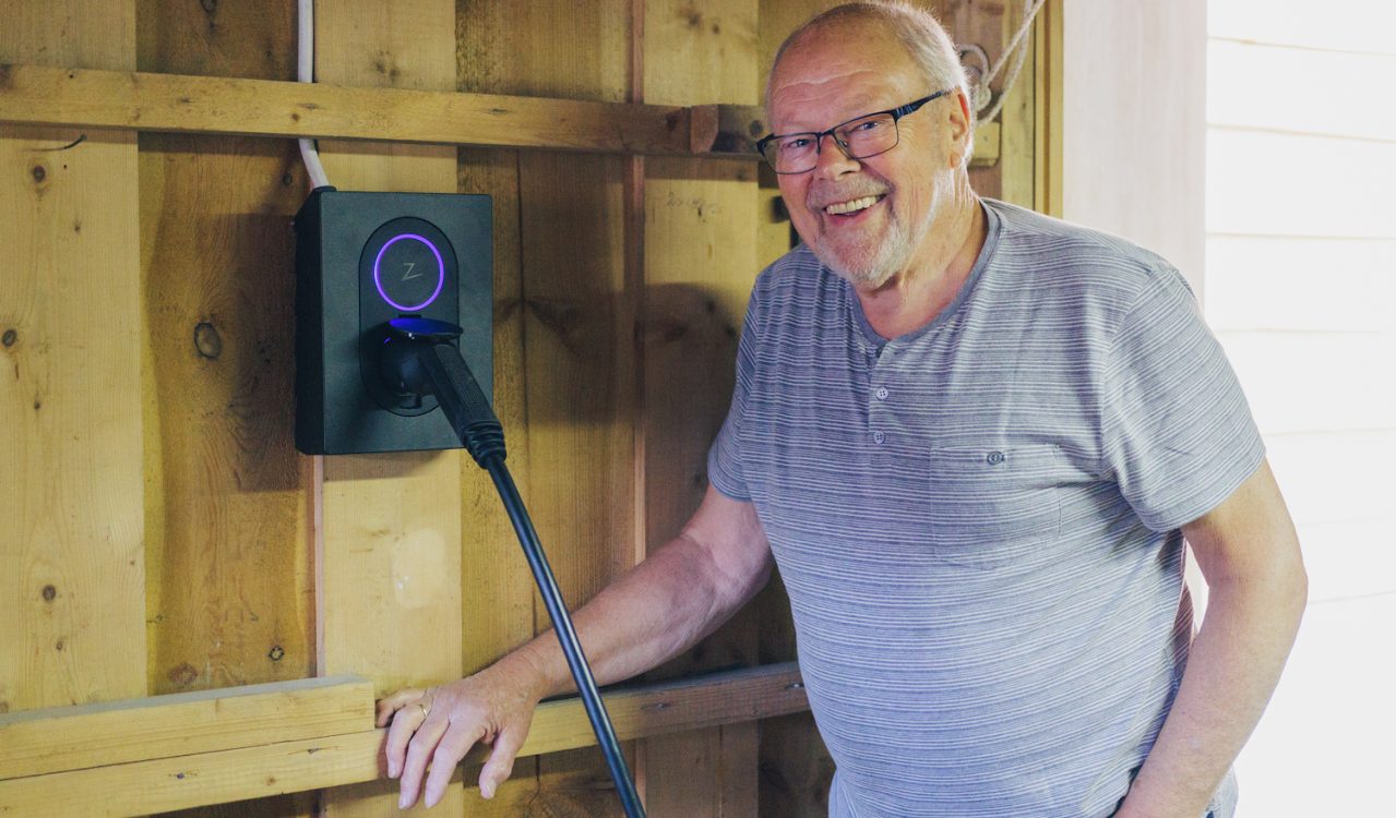 elbileier Dag Røneid-Hansen poserer smilende ved siden av sin nye moderne elbillader fra Zaptec.