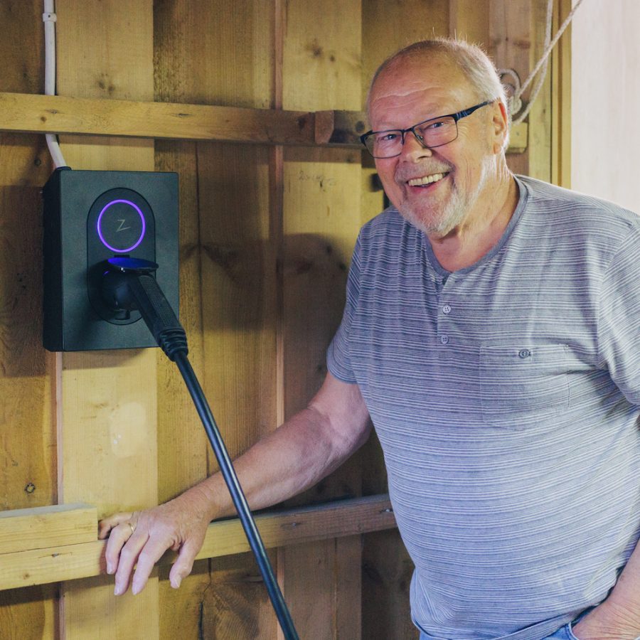 elbileier Dag Røneid-Hansen poserer smilende ved siden av sin nye moderne elbillader fra Zaptec.