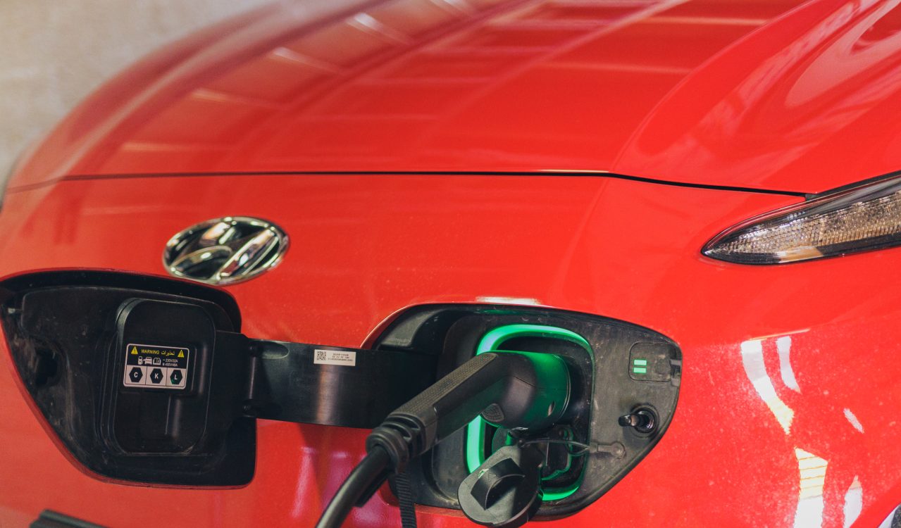 – nærbilde av rød Hyundai Kona elbil som lades.