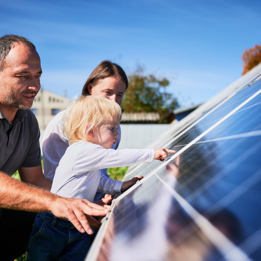 Mann, kvinne og et lite barn studerer et solcellepanel som gir Enovastøtte.