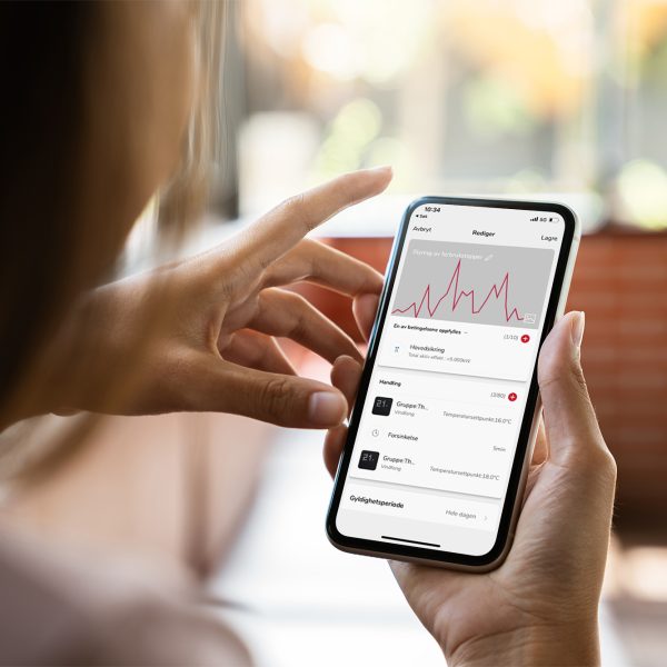 Kvinne som bruker smarthus-app på smarttelefon.