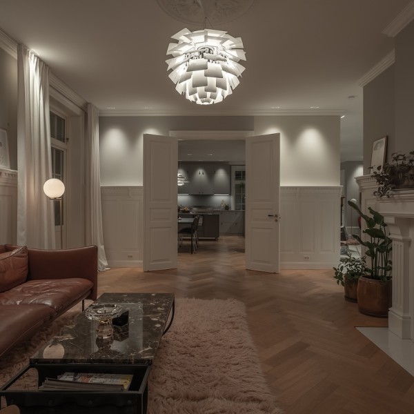 Herskapelig stue med brun skinnsofa og moderne belysning i ulike varianter.